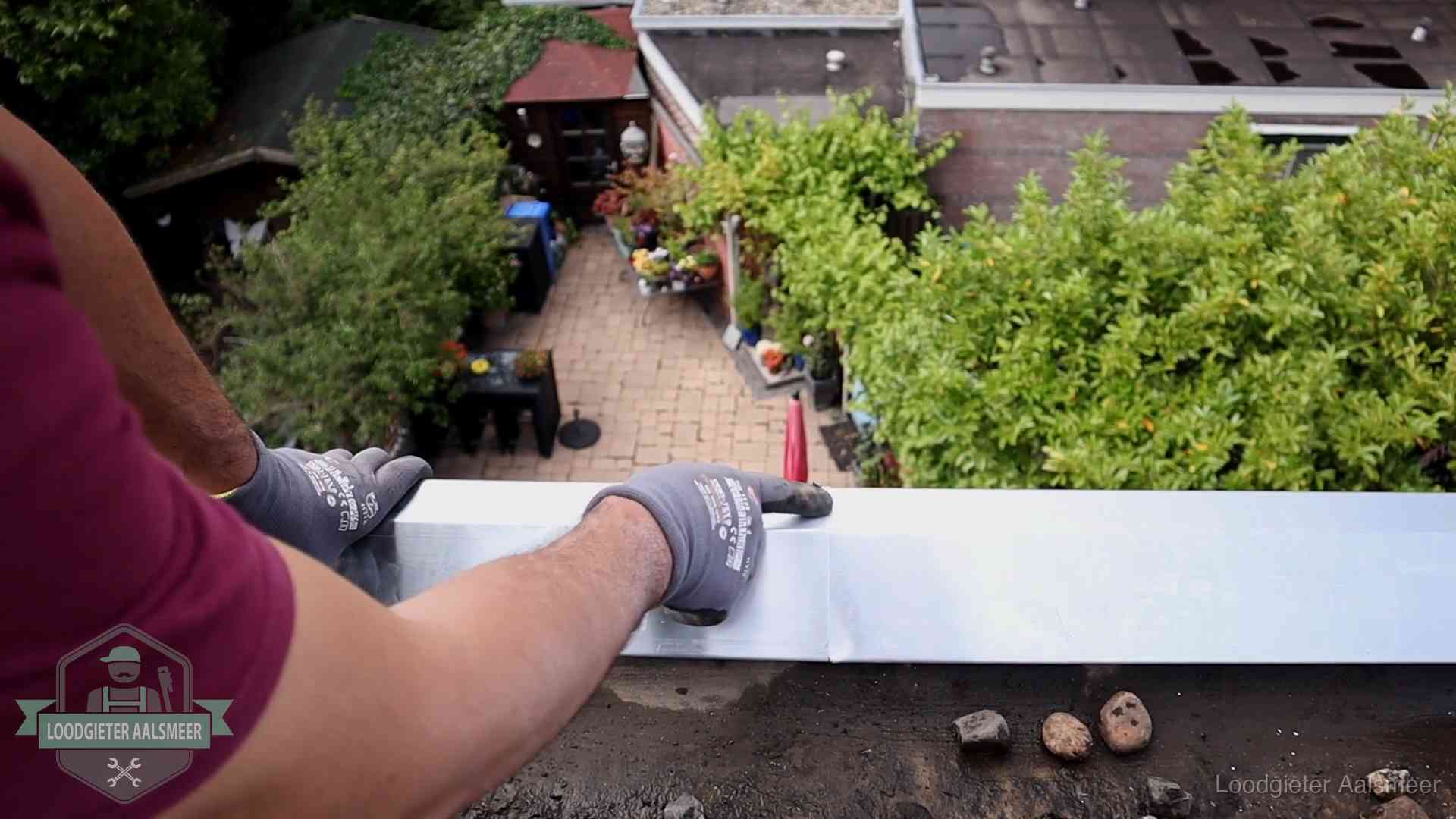 Vakman plaatst een daktrim op de dakrand van een woning in Aalsmeer