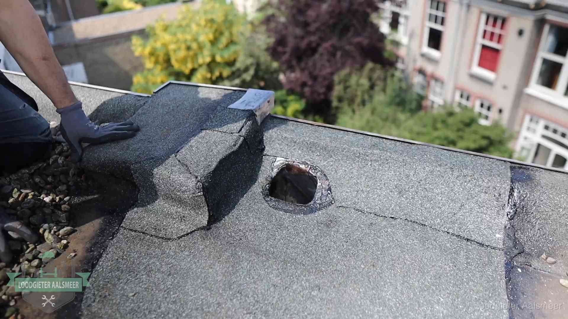 Loodgieter inspecteert een beschadigd bitumen plat dak tijdens een daklekkage-inspectie in Aalsmeer