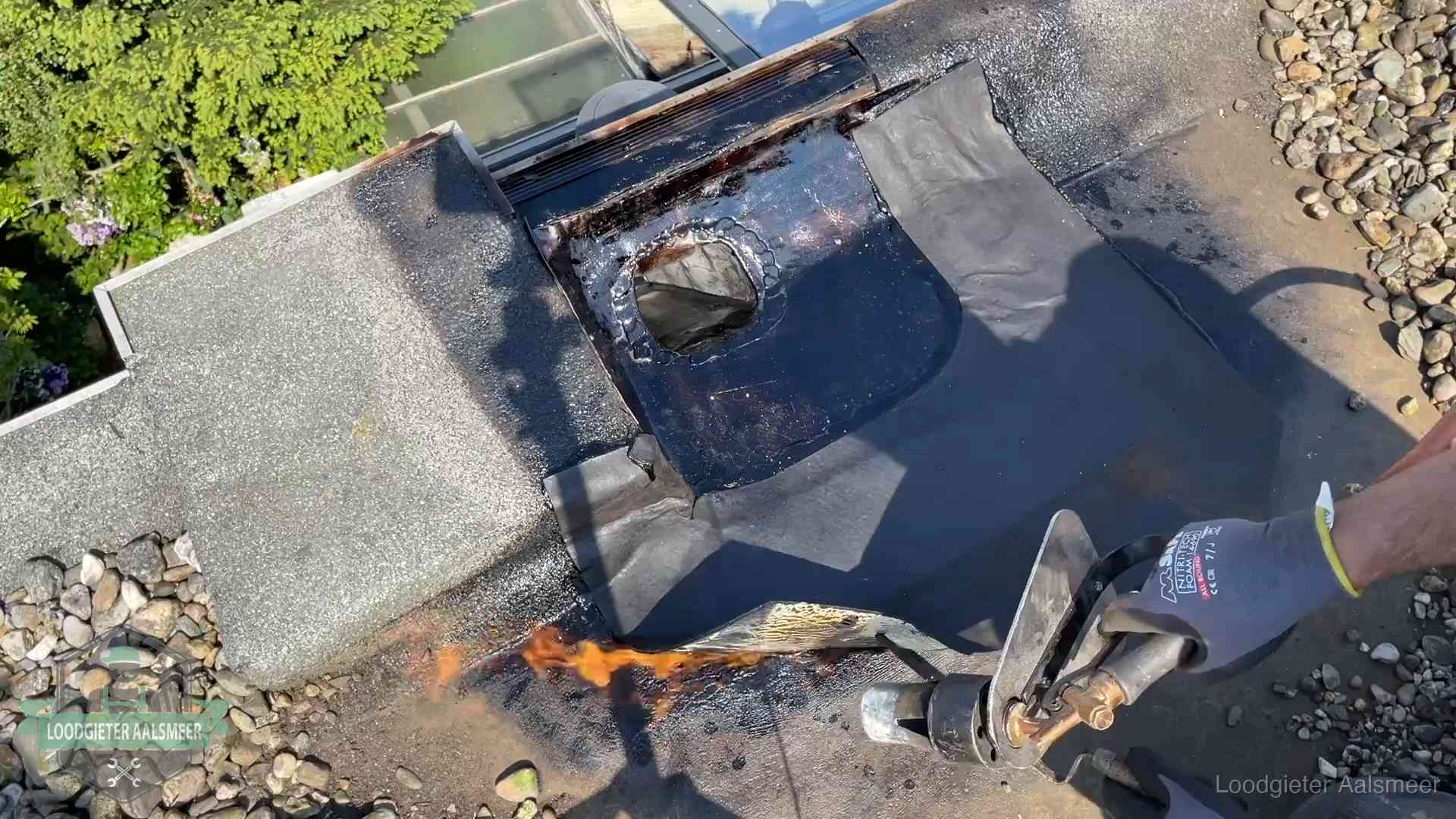 Dakdekker brandt bitumen rond een doorvoer tijdens een daklekkage-reparatie in Aalsmeer