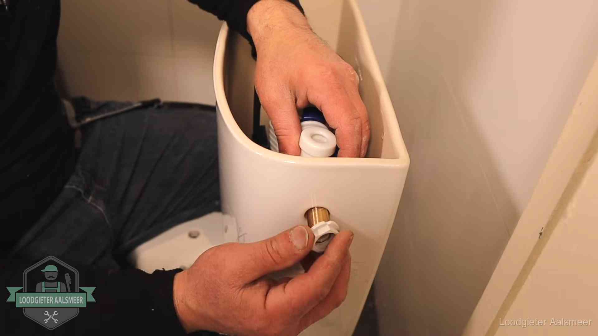 Loodgieter monteert de vlotterkraan van een stortbak bij een toilet in Aalsmeer