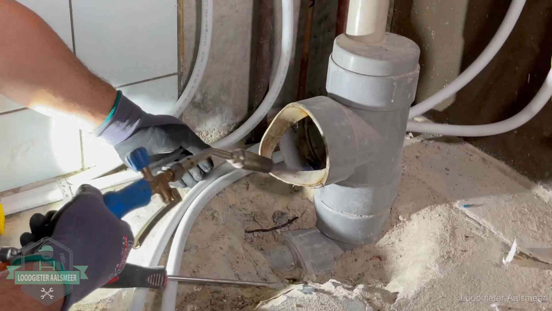 Loodgieter werkt met brander en messing kraanwerk aan leidingen in Aalsmeer