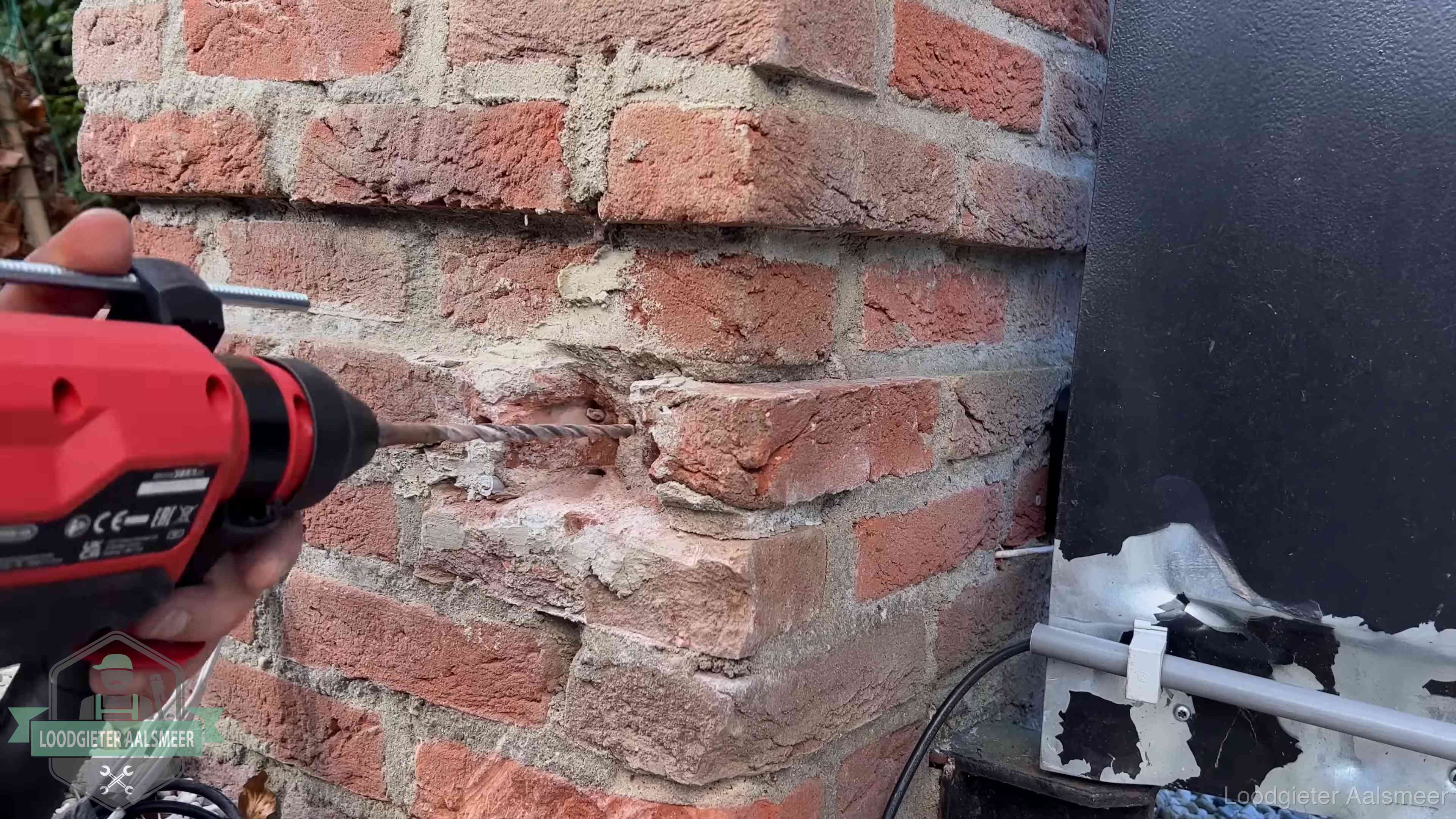 Vakman boort in de buitenmuur van een woning in de regio Aalsmeer