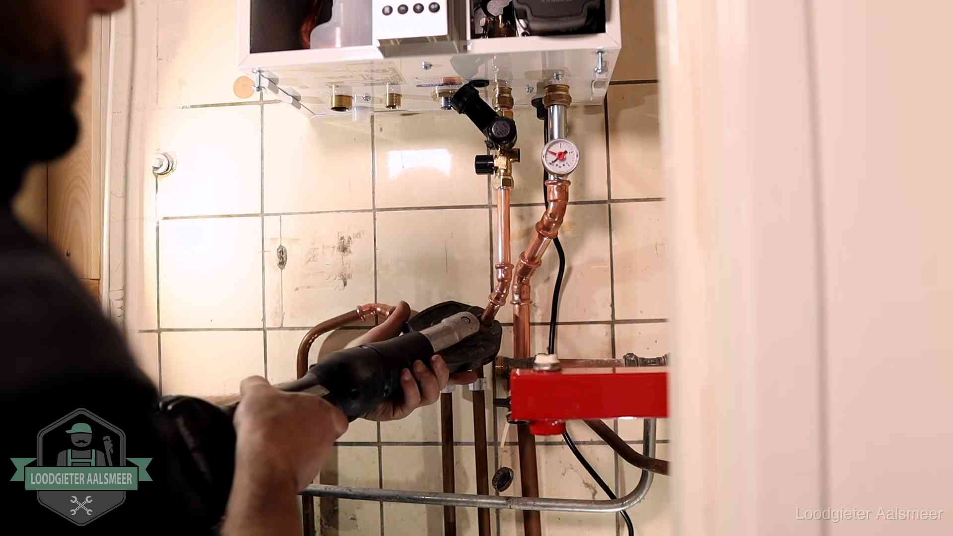 Monteur werkt aan de leidingen onder een cv-ketel in Aalsmeer