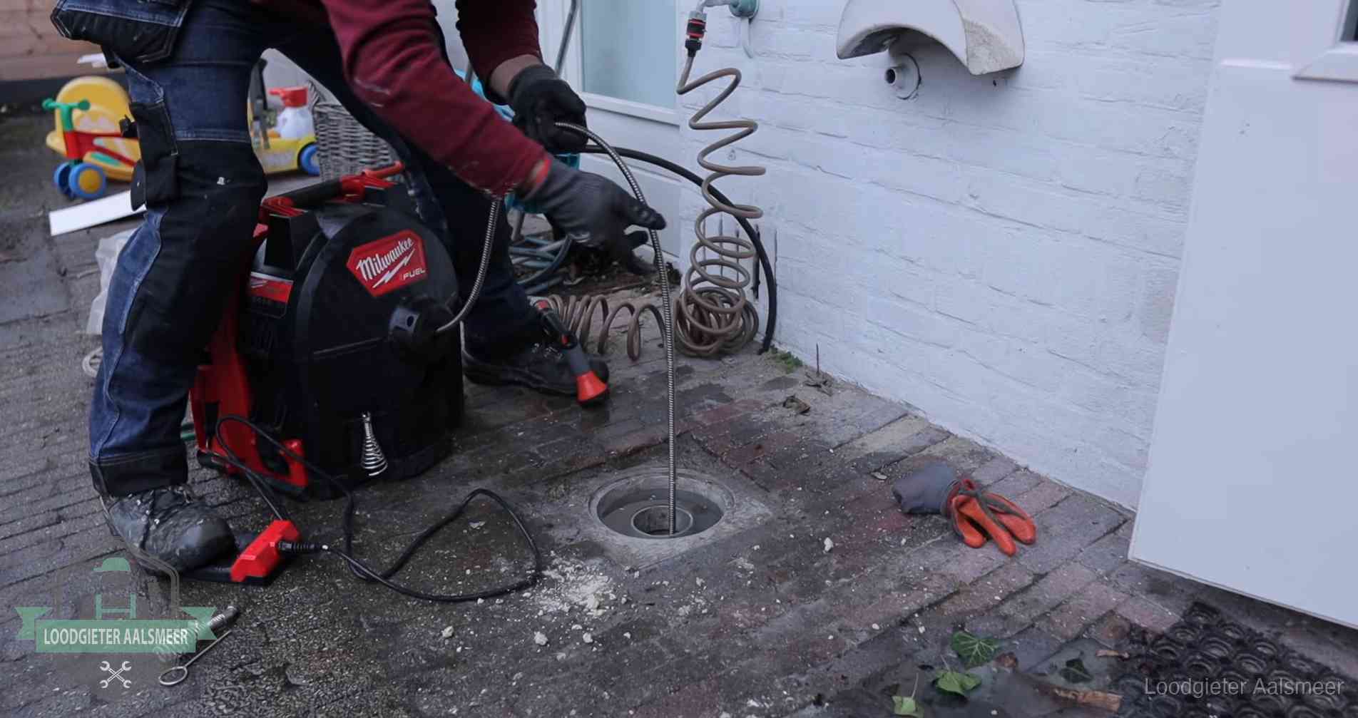 Ontstoppingsputje in de bestrating naast de gevel van een woning in Aalsmeer