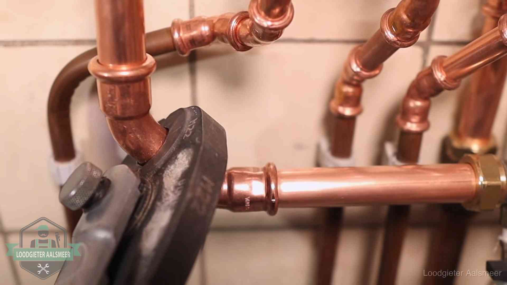 Persmachine perst een koperen fitting op nieuw leidingwerk in Aalsmeer