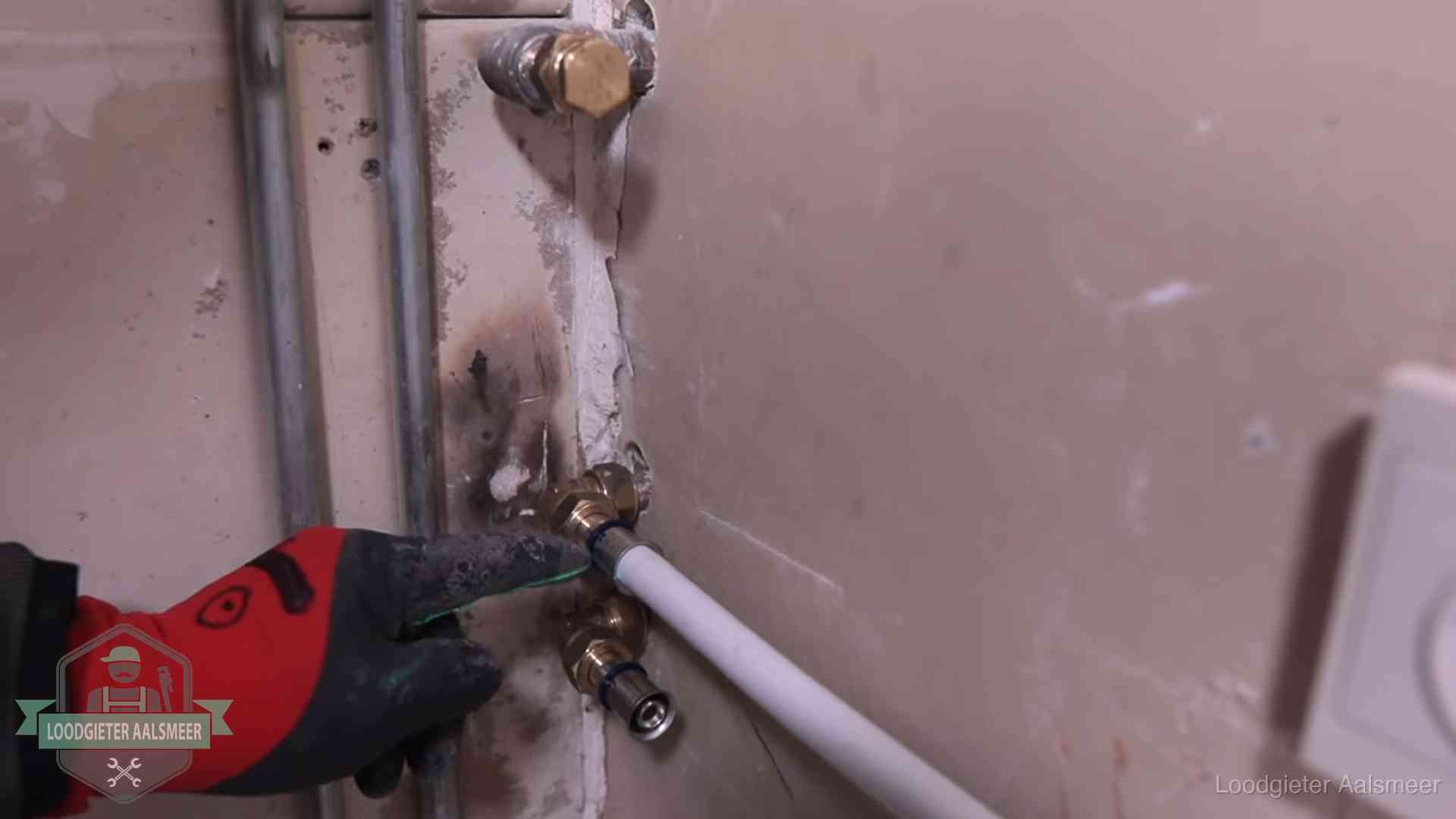 Loodgieter wijst de persfitting op nieuwe muuraansluitingen aan in een woning in Aalsmeer