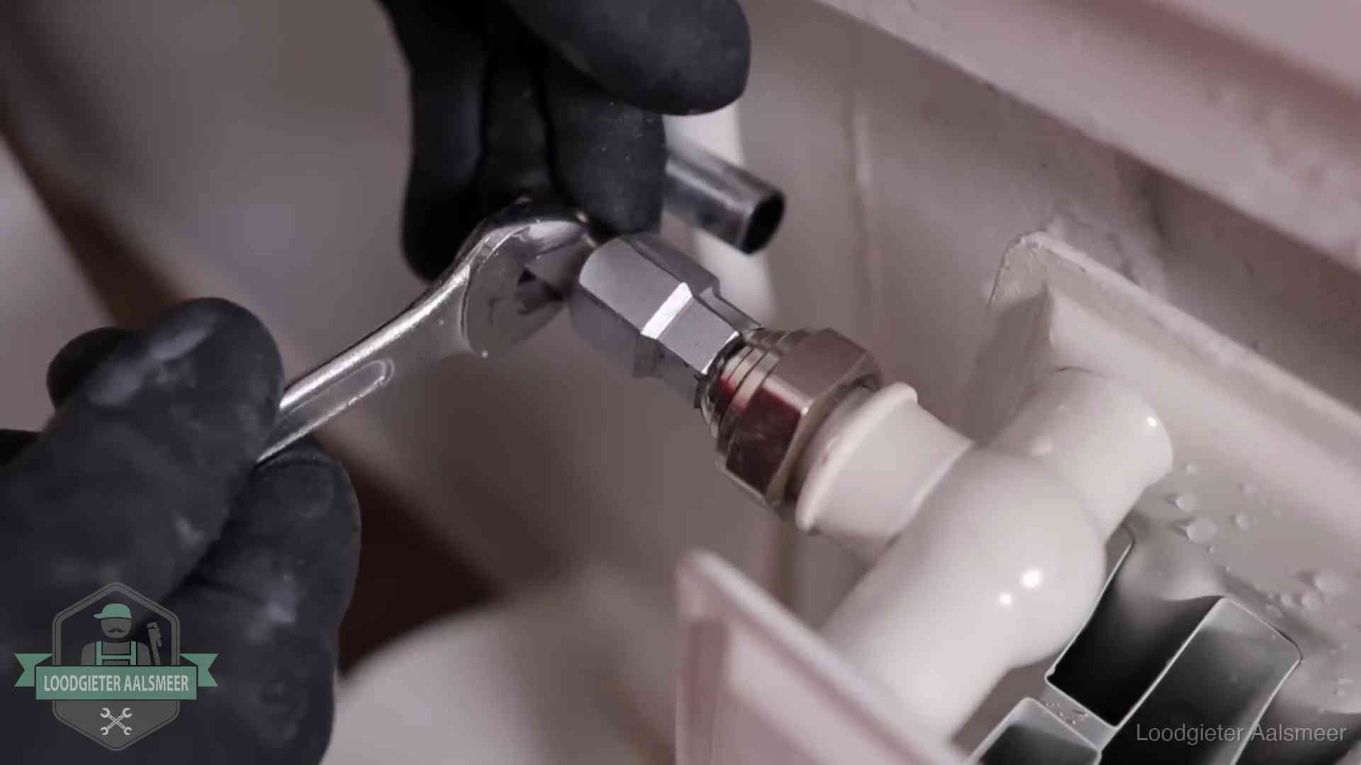 Steeksleutel draait een wartelkoppeling op een radiatorkraan aan in Aalsmeer
