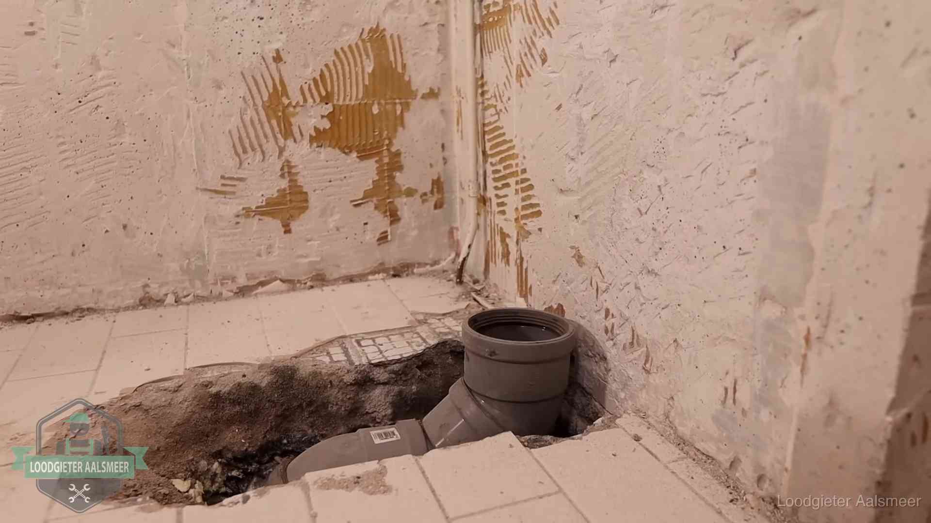 Opengebroken vloer met een nieuwe pvc-rioolbocht in een gegraven sleuf in Aalsmeer