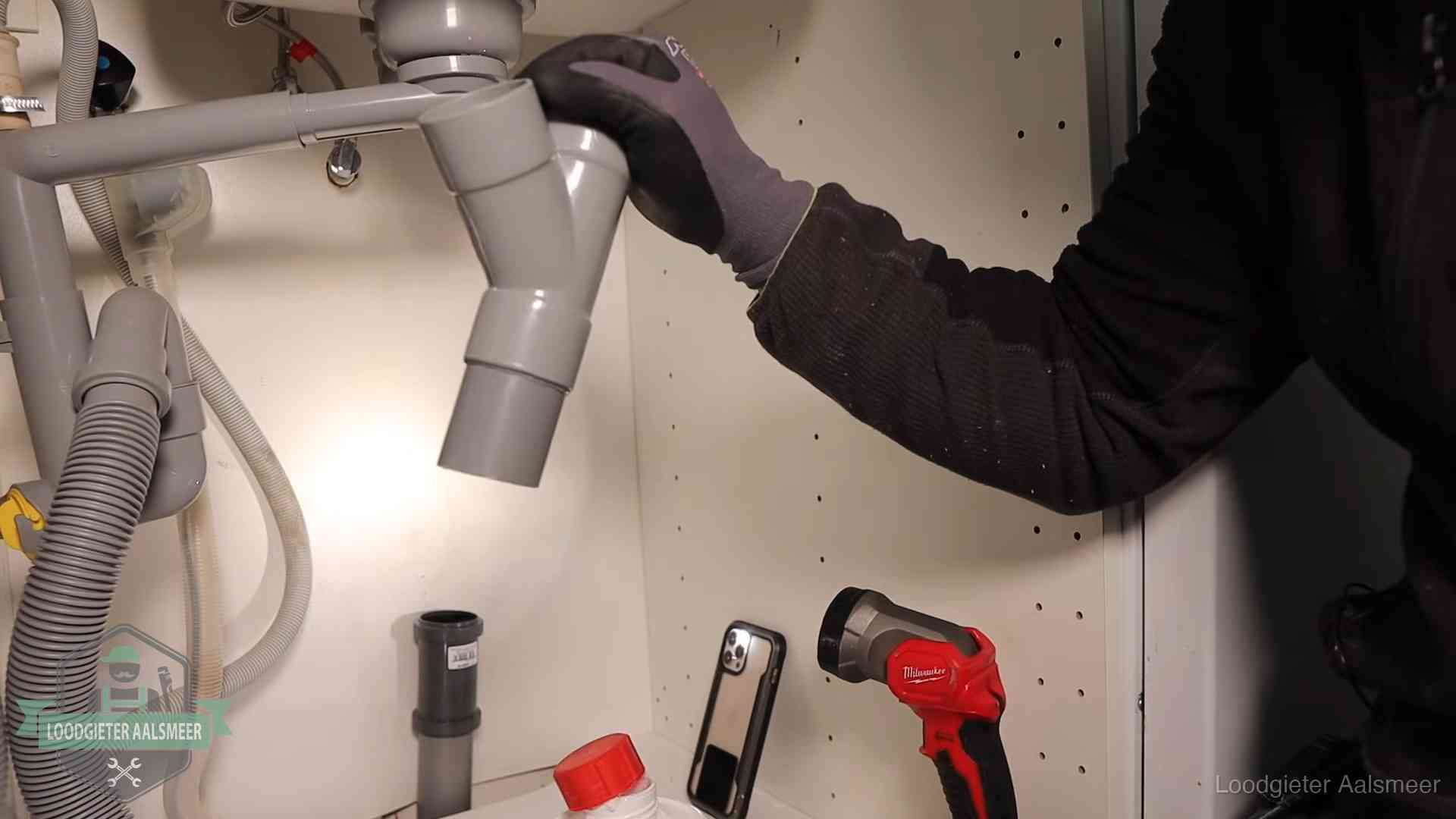 Loodgieter demonteert het sifon- en afvoerwerk onder een gootsteen in Aalsmeer bij stankklachten
