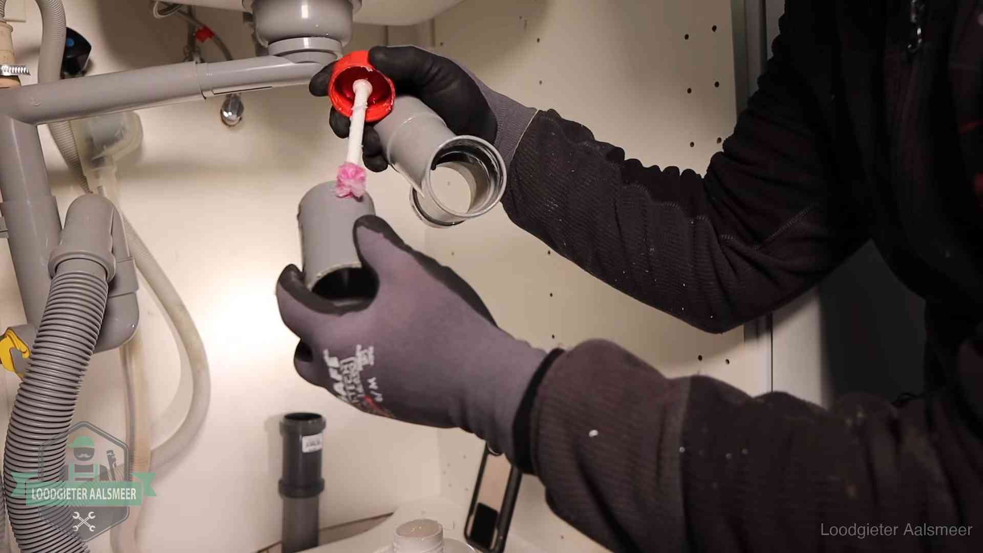 Loodgieter demonteert en reinigt de sifon onder een keukenkast in Aalsmeer
