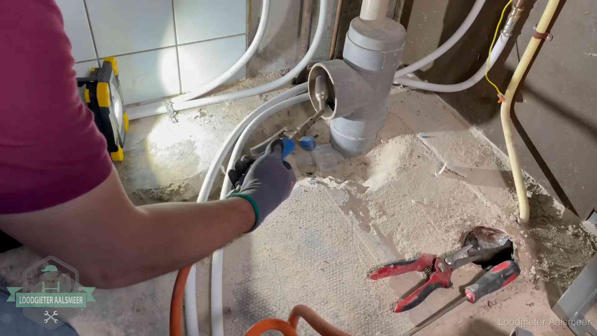 Loodgieter werkt aan leidingen bij een pvc-standleiding in een appartement in Aalsmeer