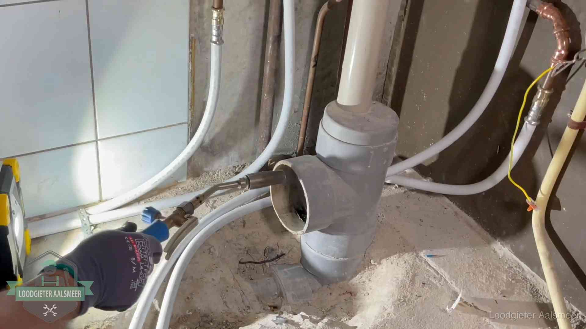 Loodgieter werkt aan leidingen bij de pvc-standleiding van een huurwoning in Aalsmeer