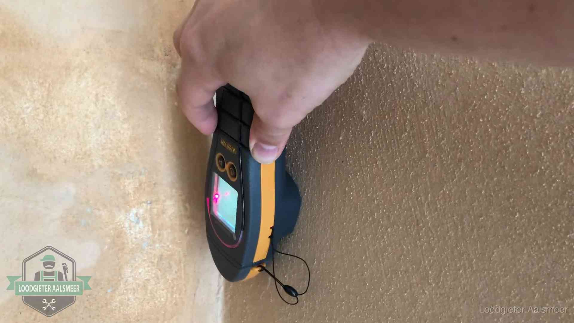 Vochtmeter tegen een muur met vochtplekken tijdens het opsporen van een daklekkage in Aalsmeer