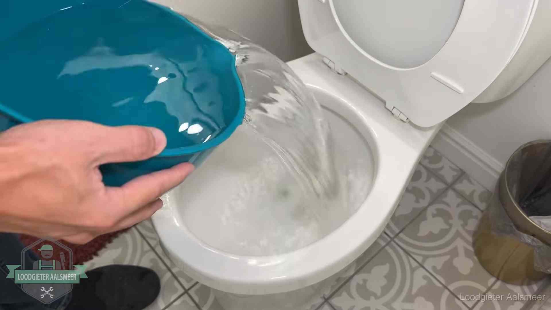 Warm water wordt voorzichtig in de wc-pot gegoten in Aalsmeer